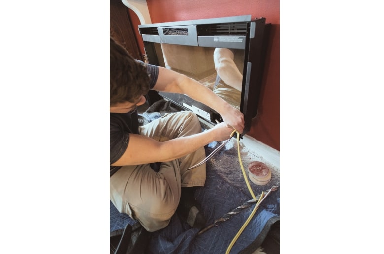 A technician is installing a new electric fireplace.