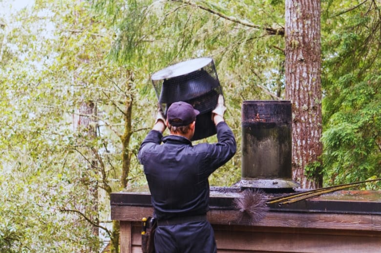 A technician doing maintenance on a chimney with a chase cover.