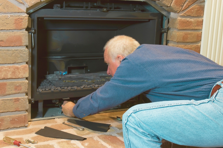 A technician doing a visual inspection on a gas fireplace.