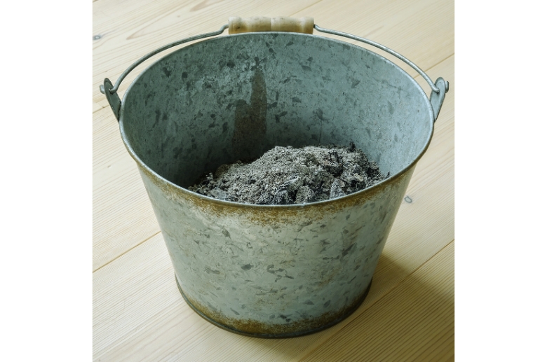Fire pit ashes in a bucket inside a house.