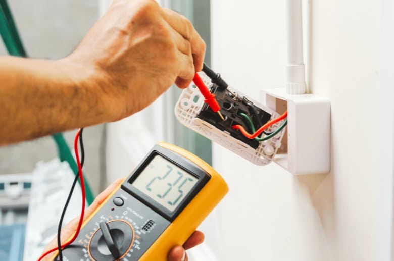A man checking the wall switch with a multimeter.