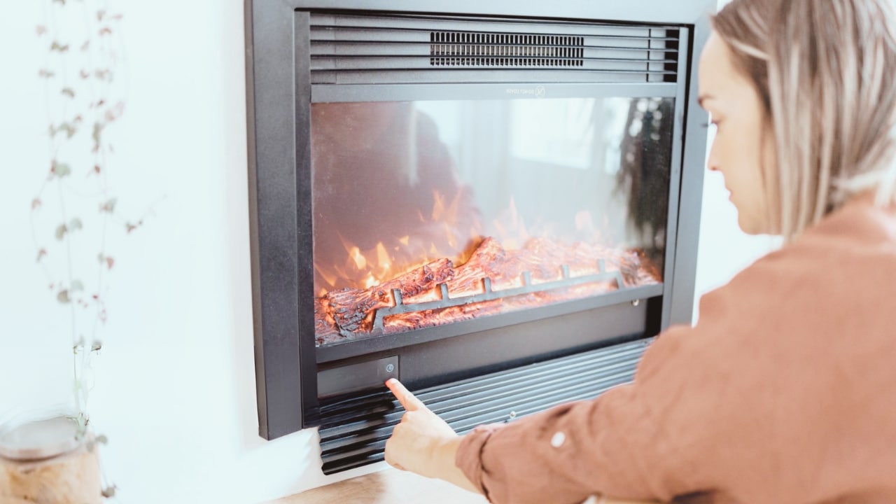 A woman operating a gas fireplace insert. Know how do gas fireplace inserts work.