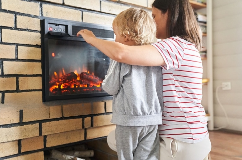 A mother is teacher her son about the electric fireplace.