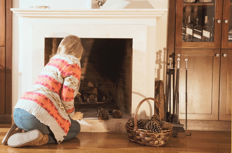 A woman checking a fireplace.