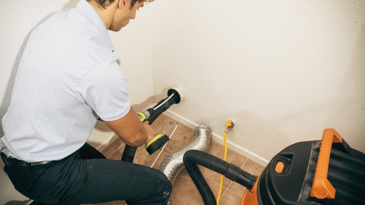 A technician is cleaning a dryer vent. Is Dryer Vent Cleaning Necessary? Find out more!