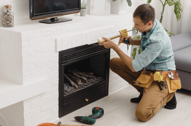 A technician is repairing a fireplace. Finding a reputable company is one of the considerations when Removing a Fireplace From Middle of House.