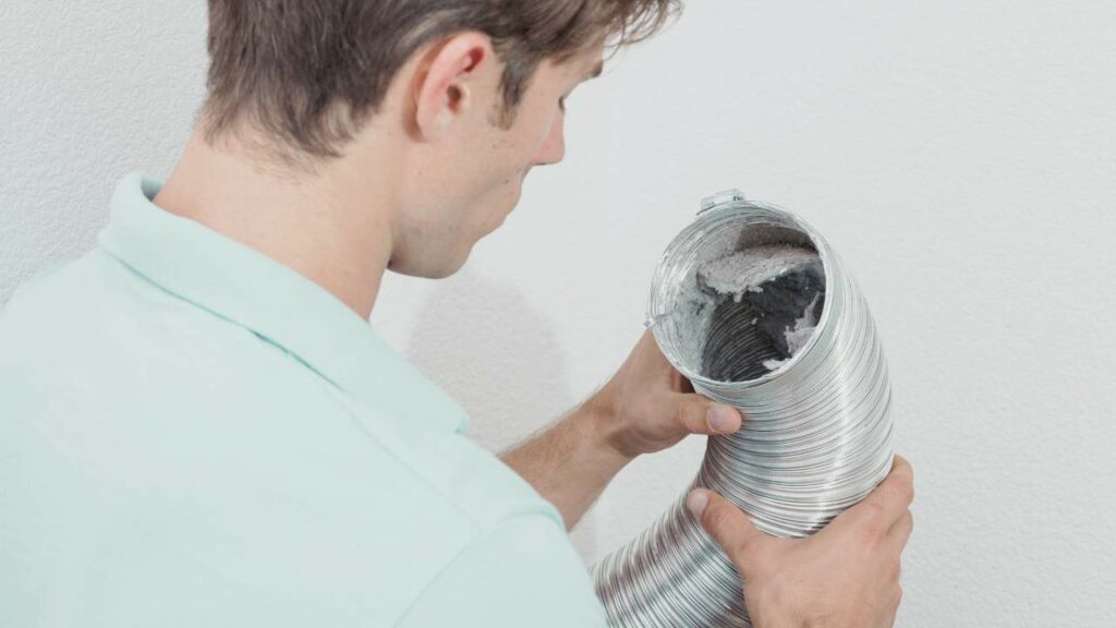 A man is looking at a dryer vent. But Who Is Responsible for Dryer Vent Cleaning? Know more!