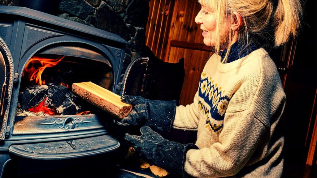 Woman is placing aspen wood inside a fireplace after researching about what to burn to clean chimney