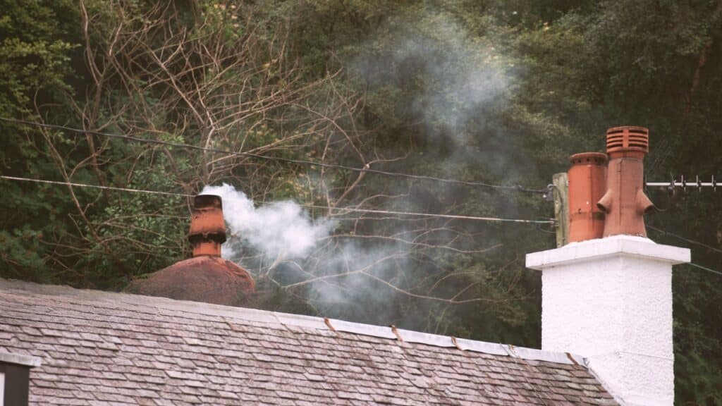 White smoke coming out of chimney on a roof.