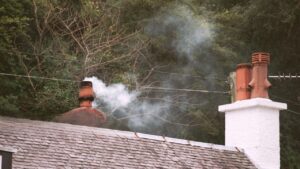 White smoke coming out of chimney on a roof.