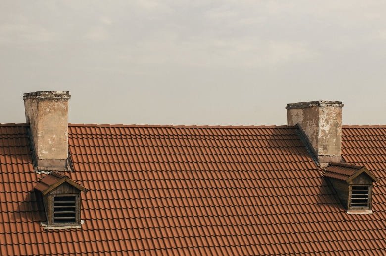 Two chimneys on the same roof of the same house.