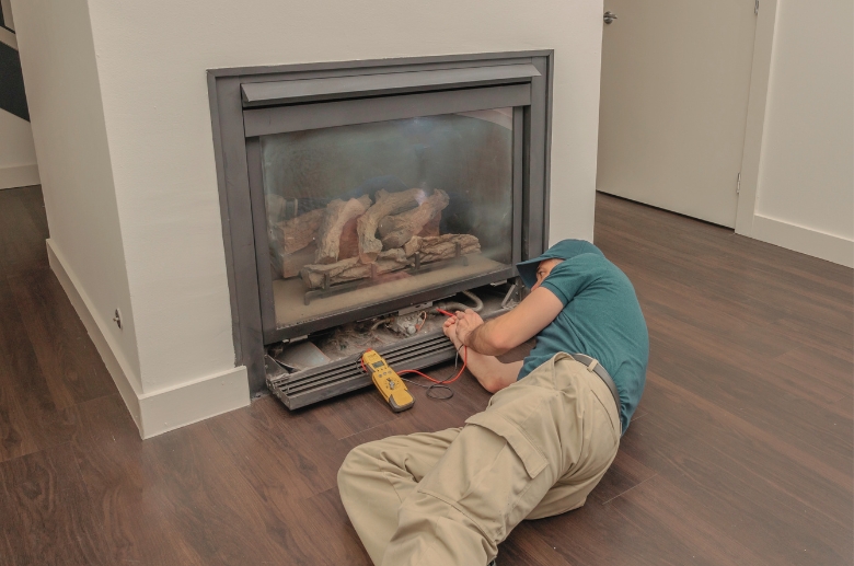 A gas fireplace technician checking the fireplace.