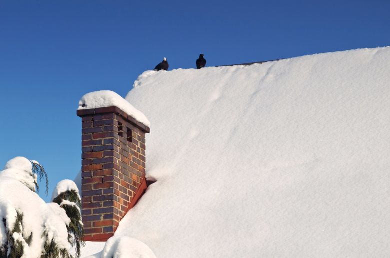 snow on top of spalling brick chimney